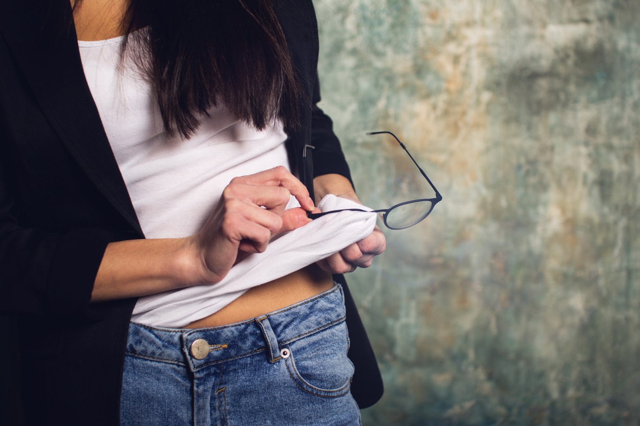 woman wiping her eyeglasses using her shirt