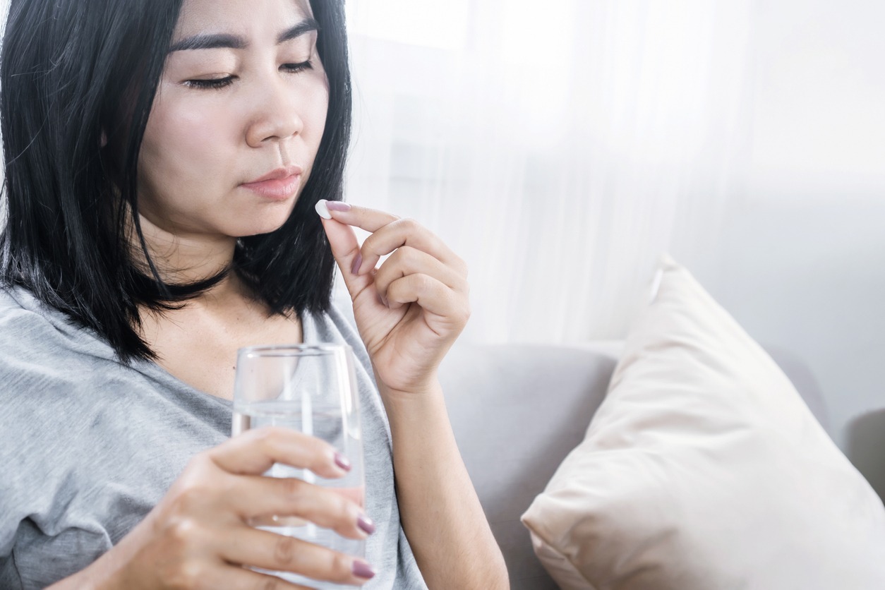 woman taking medicine with a glass of water