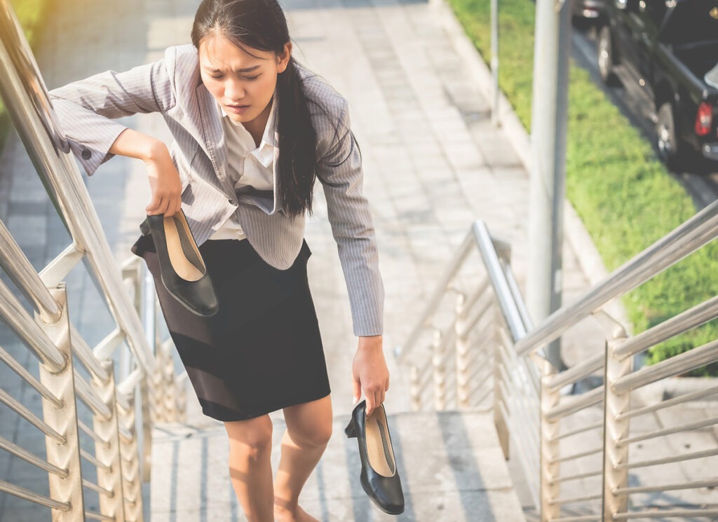 woman removing high heels due to fatigue
