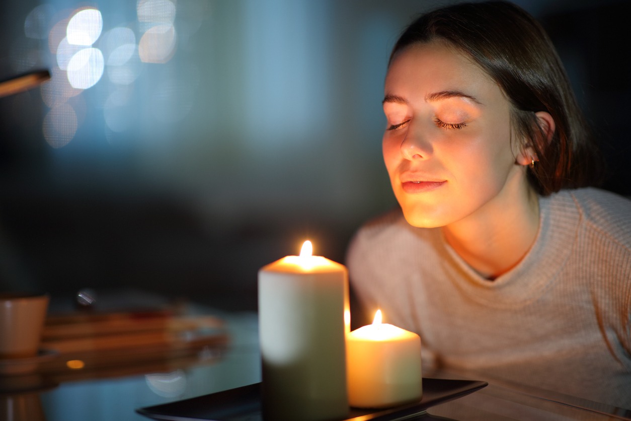 A woman smelling a lighted candle in the night