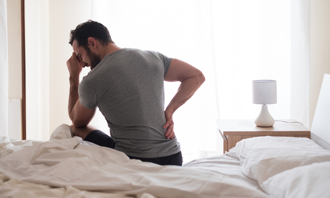 man on a bed experiencing back pain