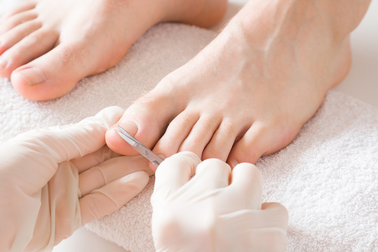 hand with gloves cutting toenails of another person