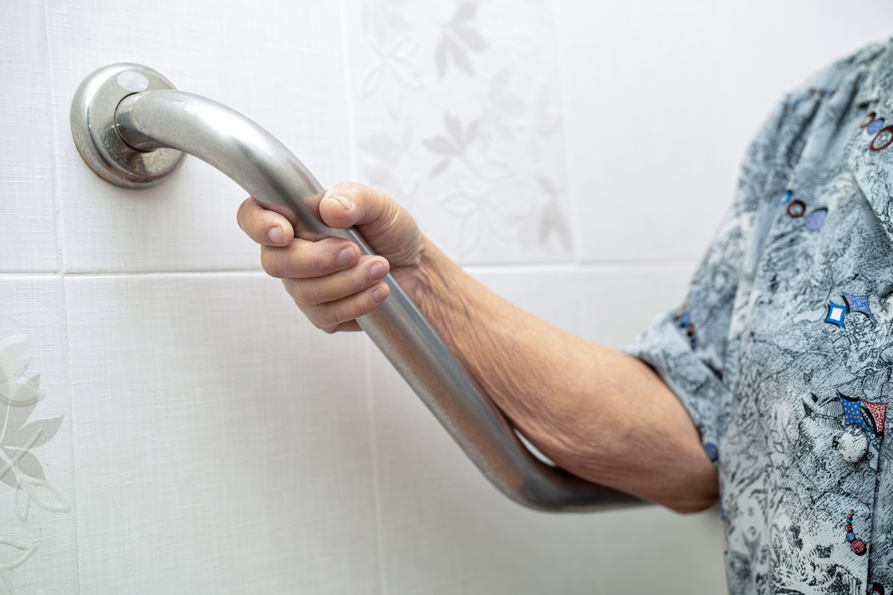 elderly woman holding onto a bathroom handrail