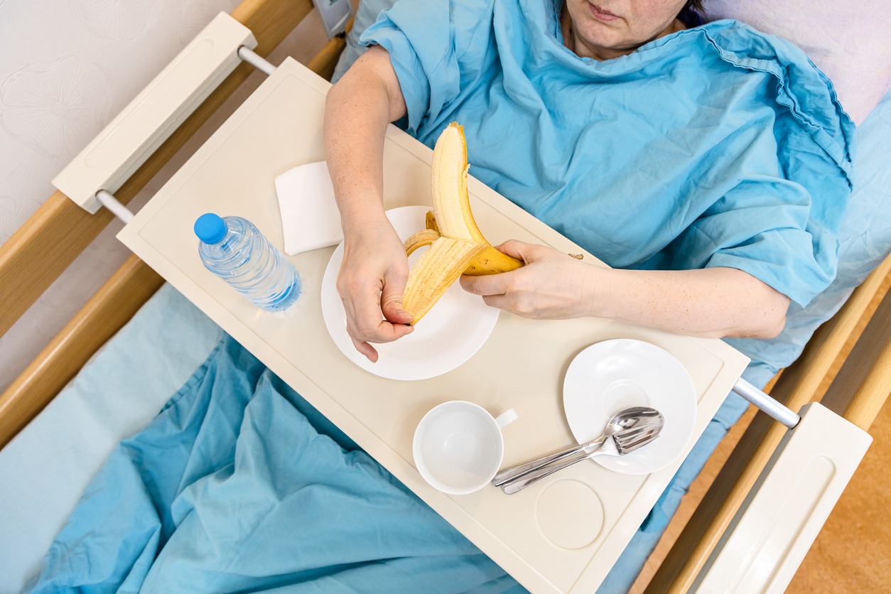 woman in a hospital eating on an overbed table