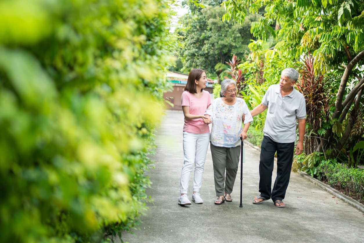 a senior woman using a walking cane while walking with her loved ones