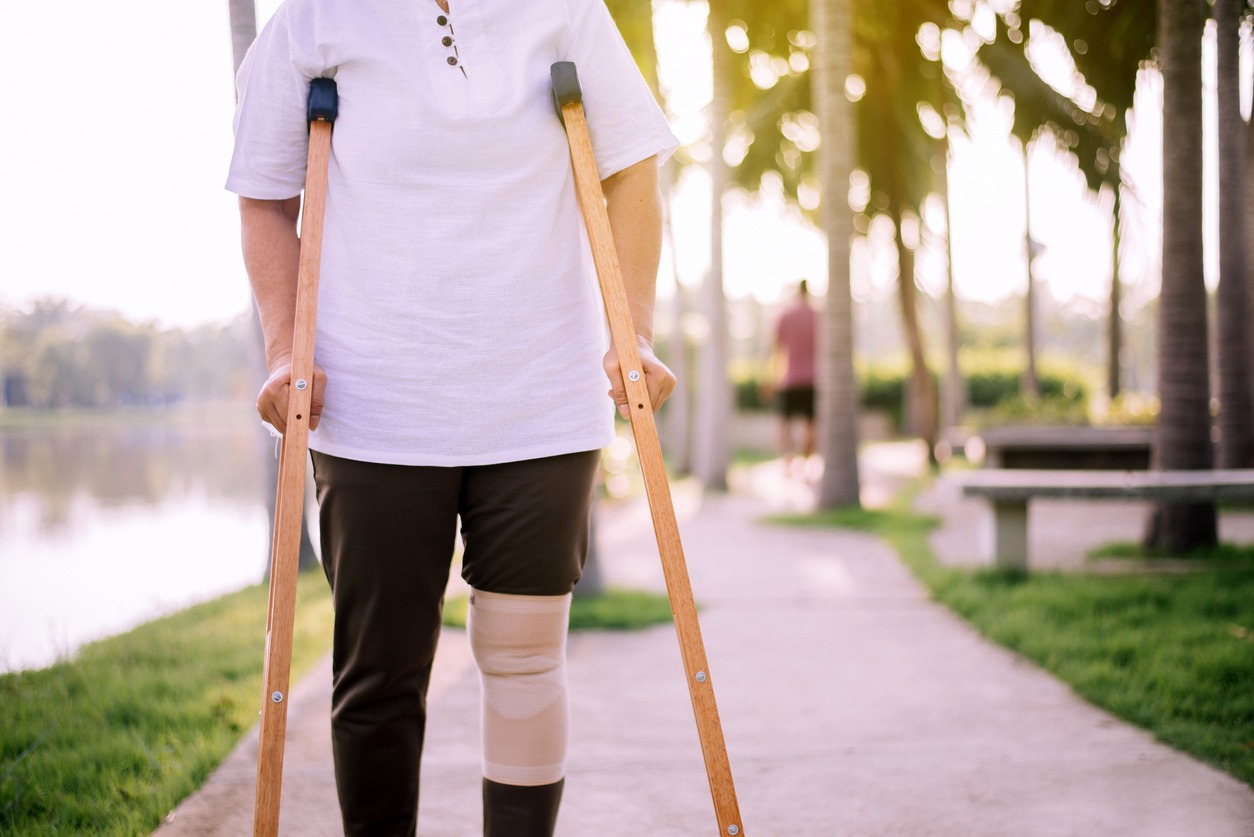 senior walking using underarm crutches