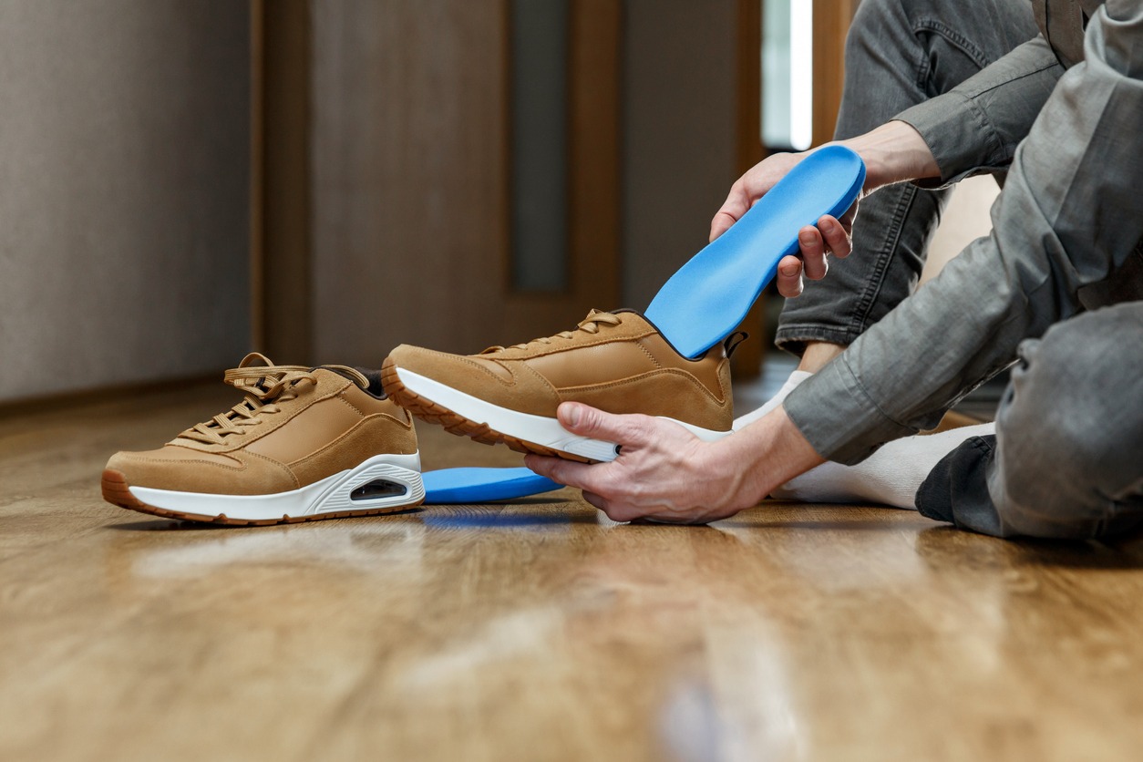 man putting insole with arch support inside a shoe