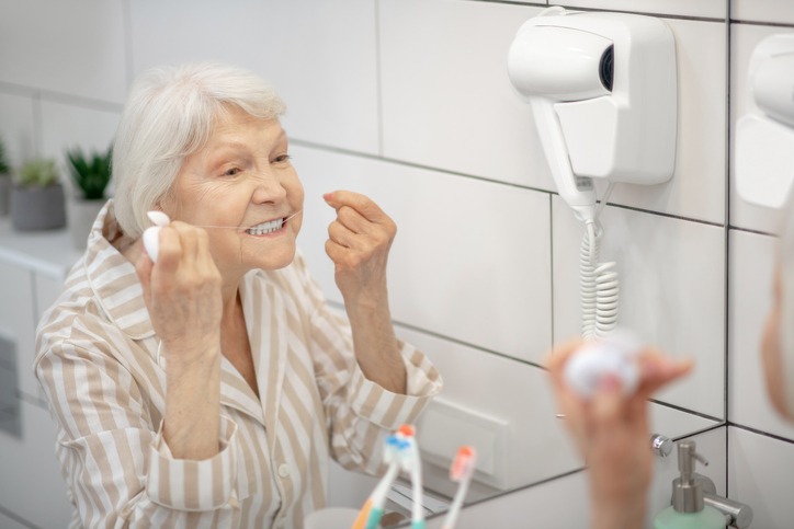 senior woman flossing her teeth