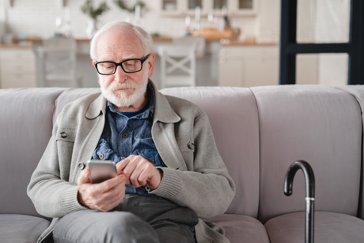 senior man with a cane beside him on the sofa