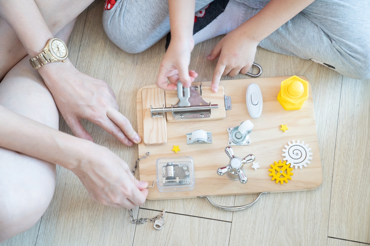 an adult and a child playing with a busy board