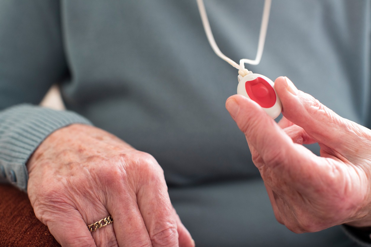 elderly person holding an alarm on a string or cord