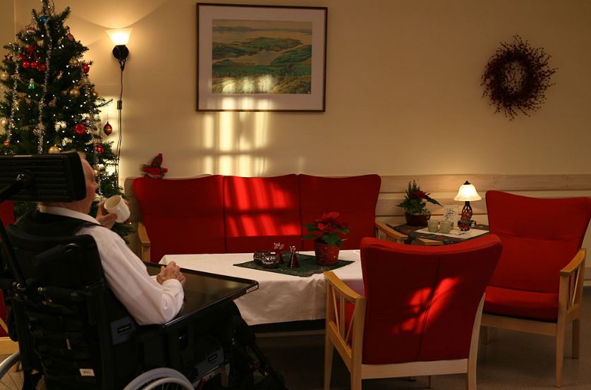 An old man at a nursing home holding a cup