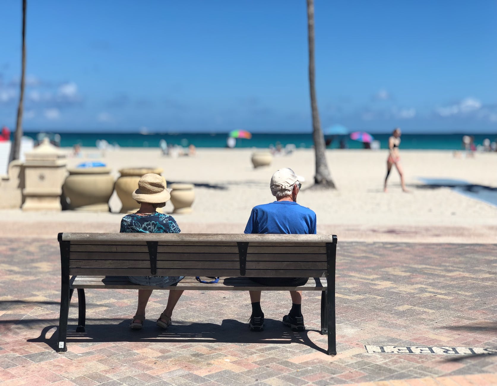 Elderly couple sitting on a bench at a beach and enjoying their time