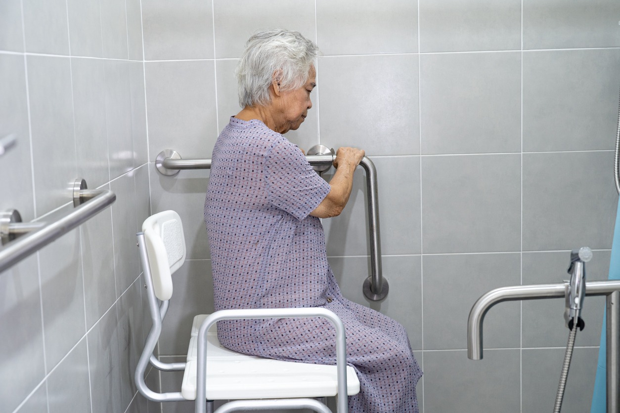 a senior woman using a shower chair in the bathroom