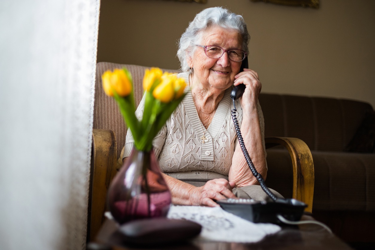 a smiling senior woman smiling while using the telephone