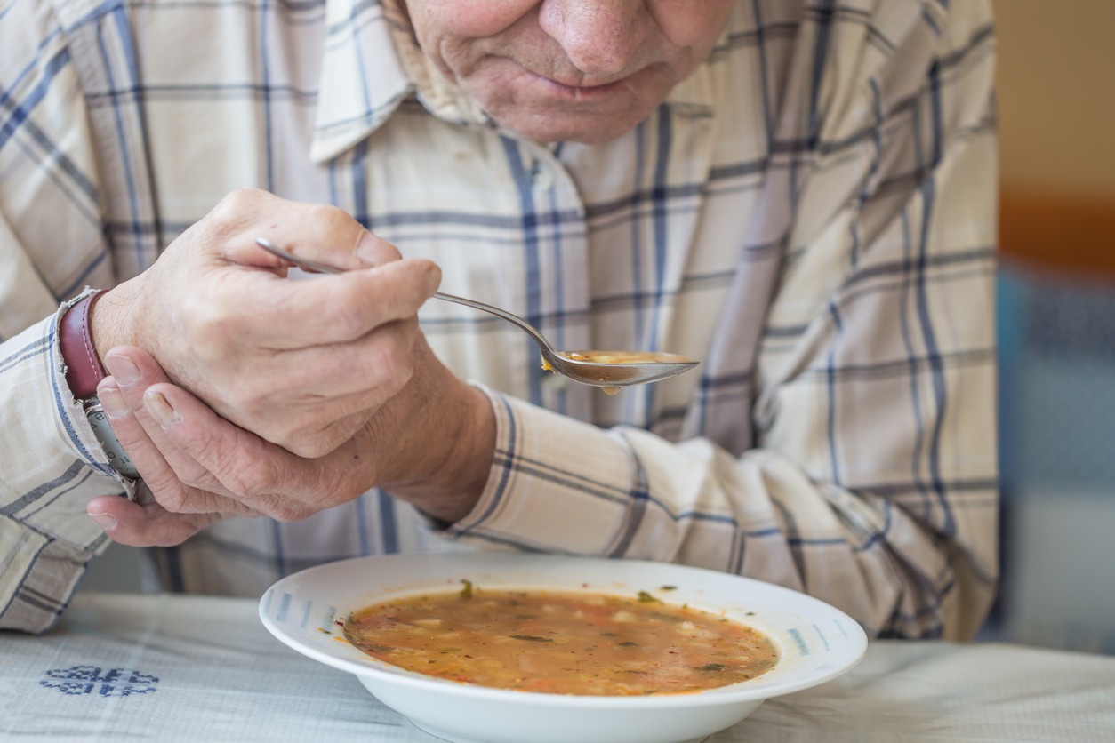 an elderly man eating soup