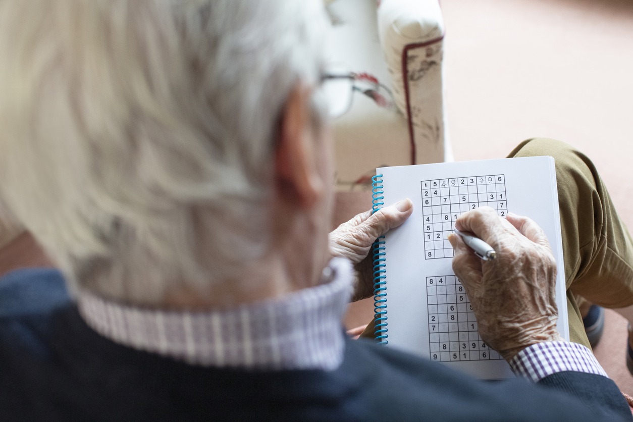 an elderly man playing sudoku