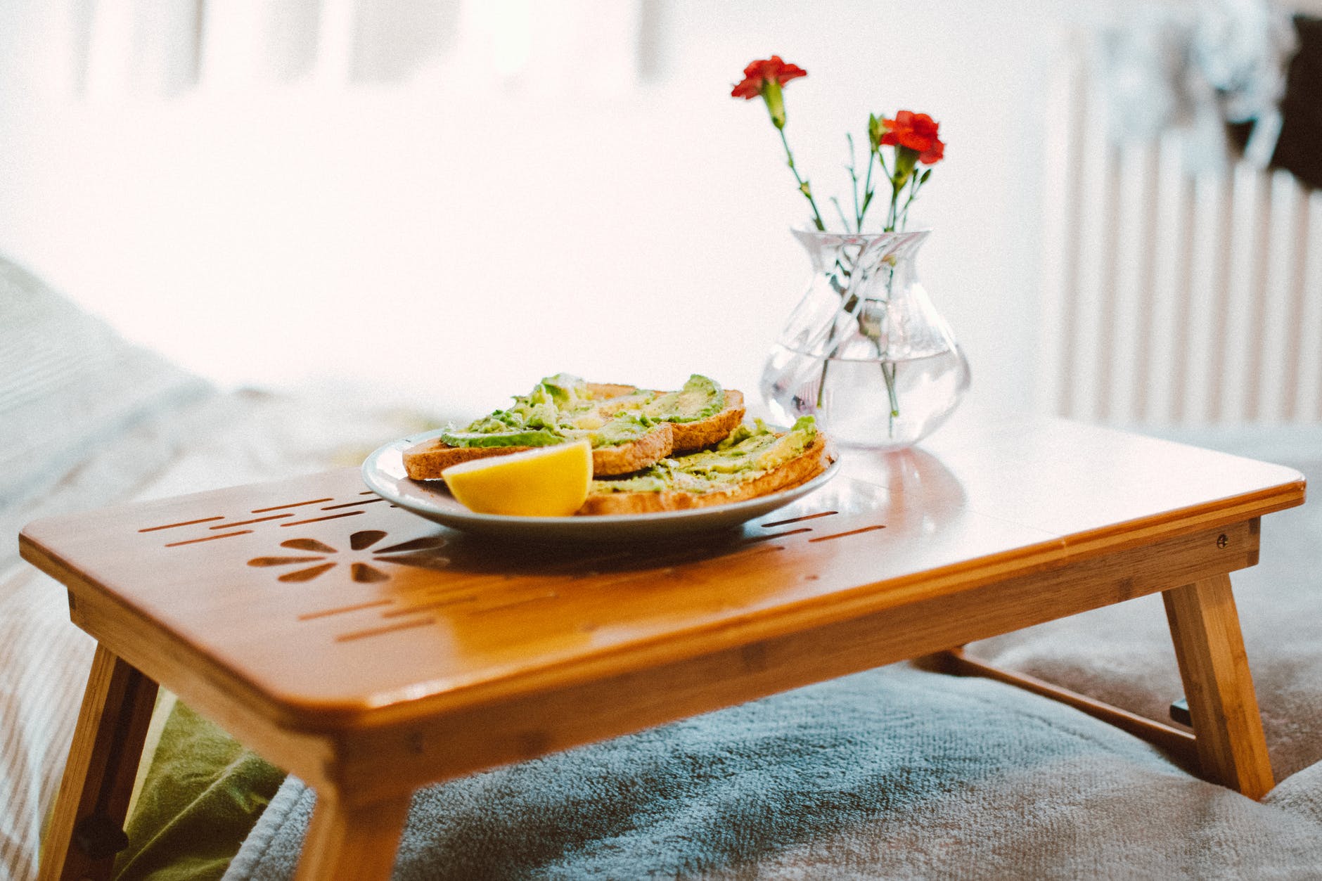 breakfast and a vase with flowers on an overbed table