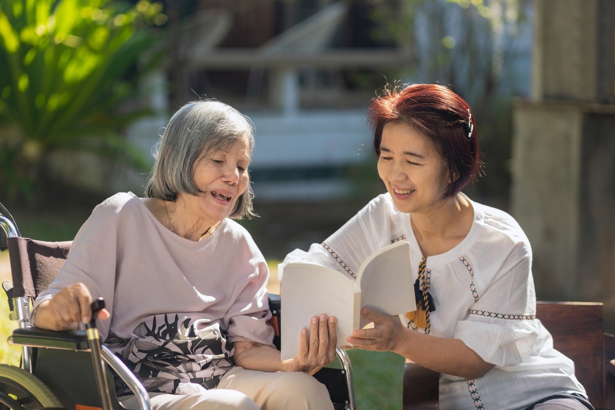 senior woman with dementia reading a book with her daughter