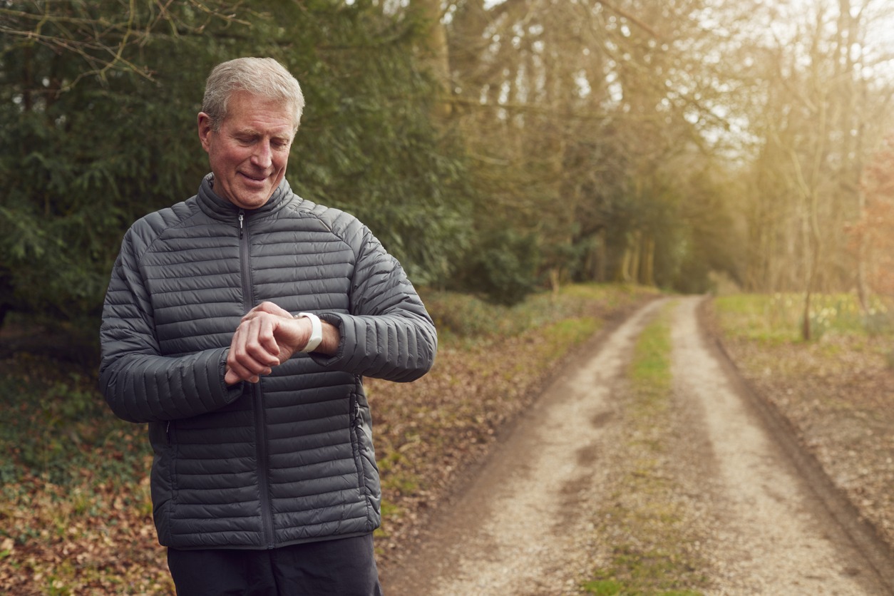 a senior man with a smartwatch walking outdoors