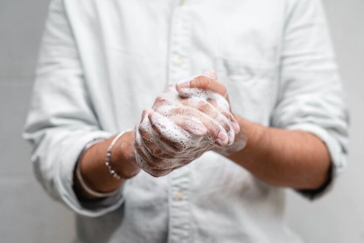 A person in white clothes washing hands with soap