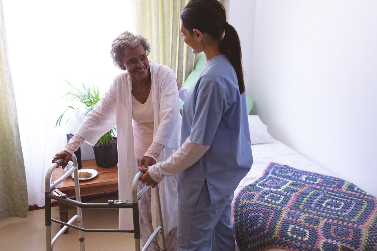 caregiver assisting a senior patient with a walker