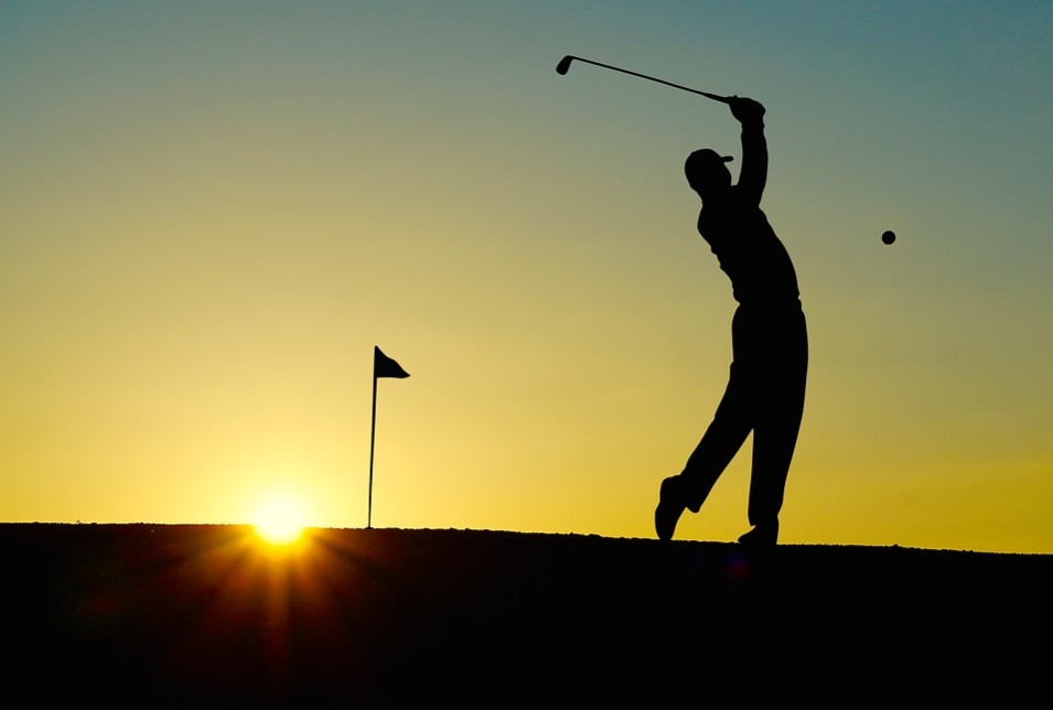 A man playing golf at sunset