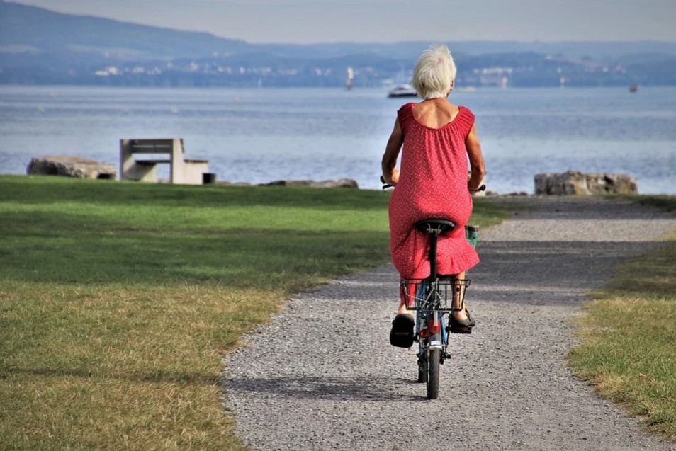 A senior woman cycling by the shore