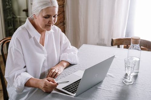 An elderly woman working on a laptop