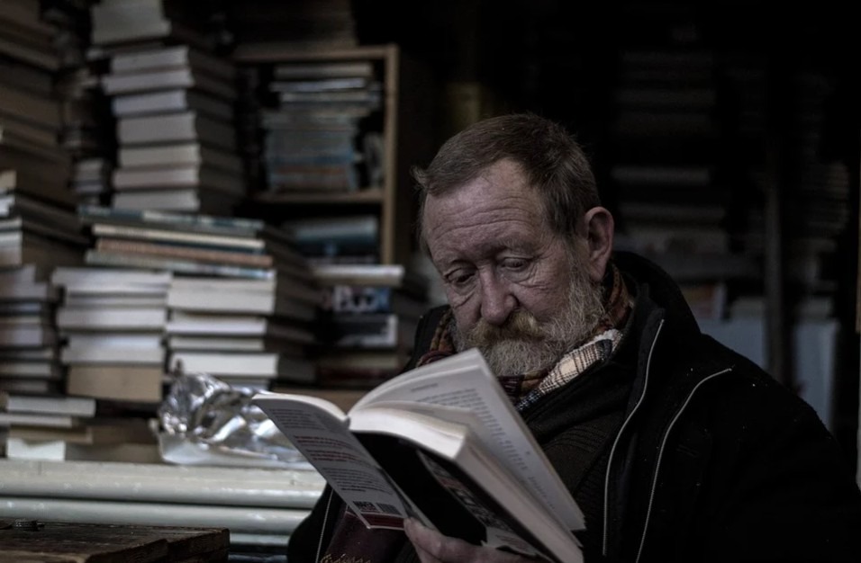 An old man engrossed in reading a book
