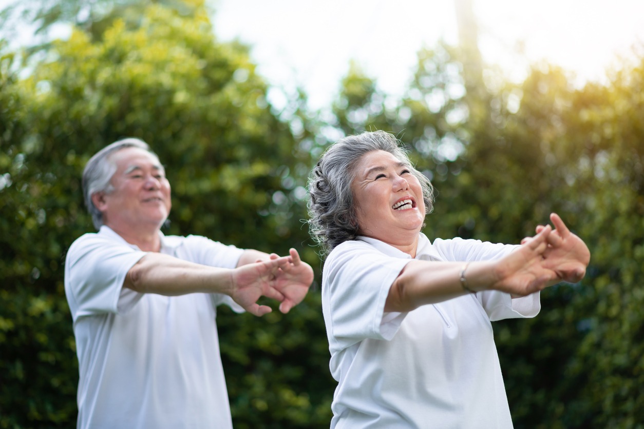 Happy Asian senior couple stretching hands before exercise at park outdoor. Smiling People in white shirts