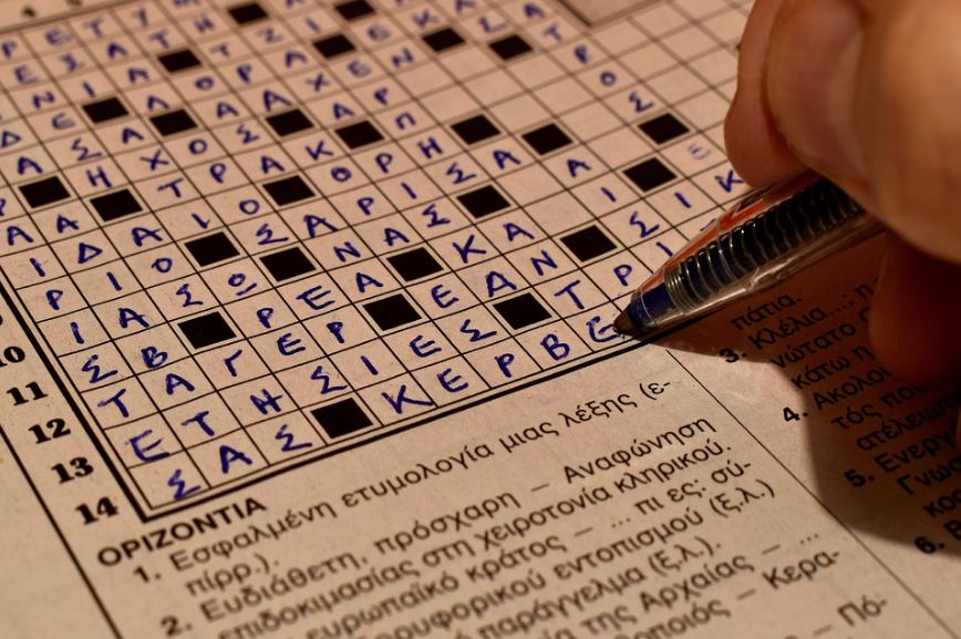 Image of man filling crossword puzzle.
