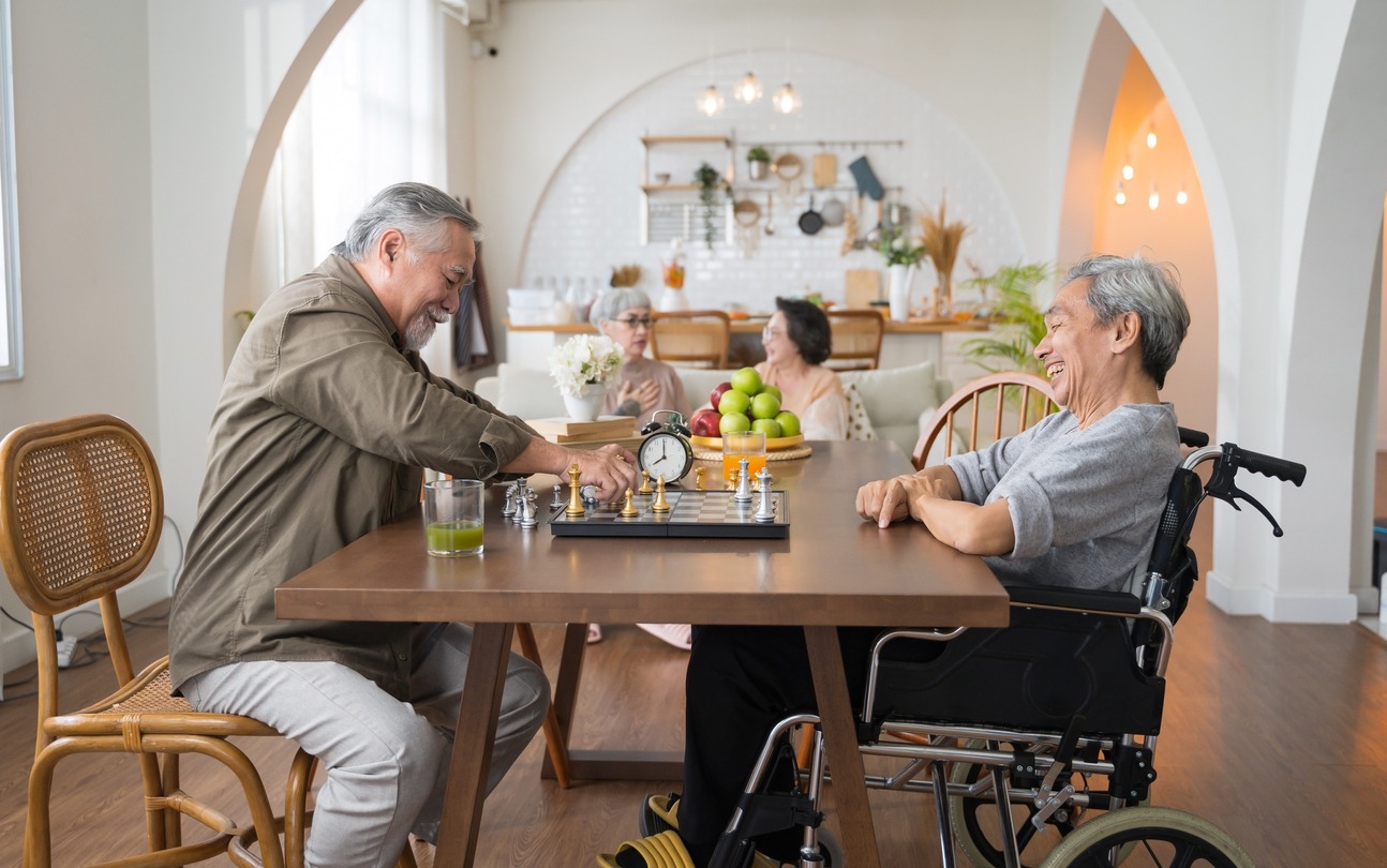 Portrait of two Asian senior men playing chess in a nursing home