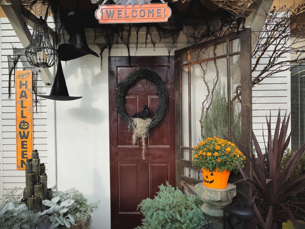 Spooky front entrance Halloween decor. Welcome sign, wreath on the door
