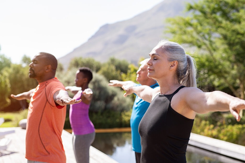 A group of mature people doing breathing exercises outdoors