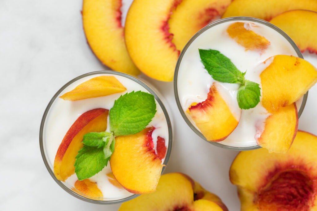 peach yogurt with mint in glasses with fresh fruits on a white marble table. healthy breakfast. top view