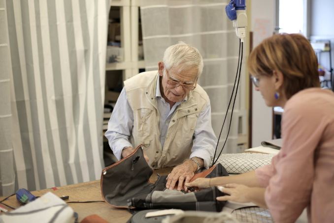 senior-male-artisan-creating-bag-together-with-female-assistant