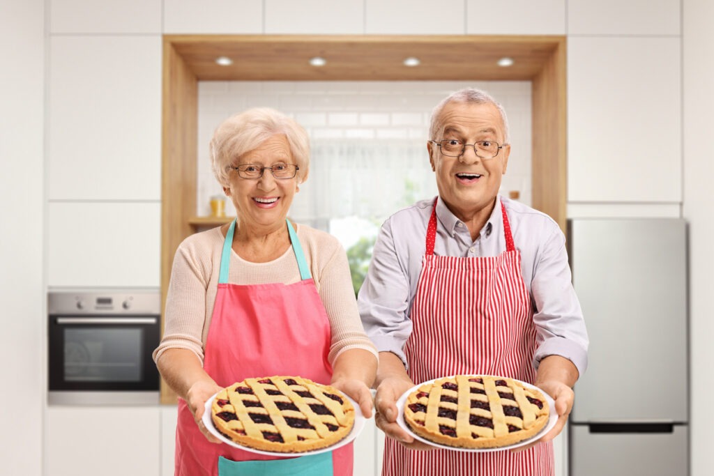 Senior man and woman holding pies in a kitchen