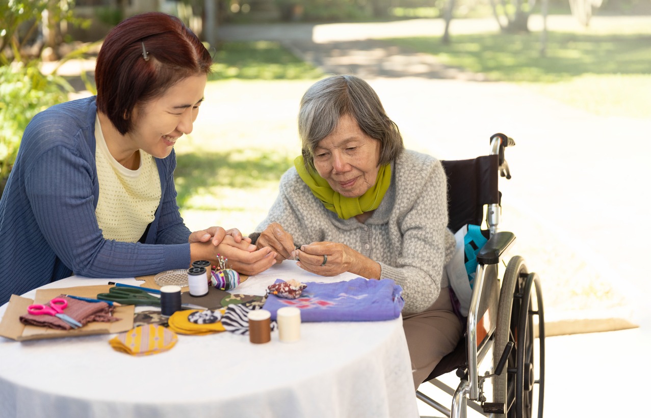woman assisting a senior with arts and crafts