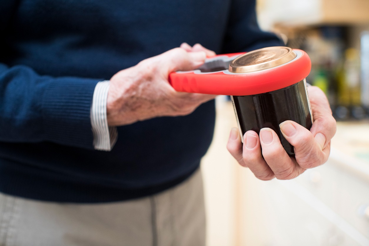 a senior man using a jar opener to take off the lid of the jar