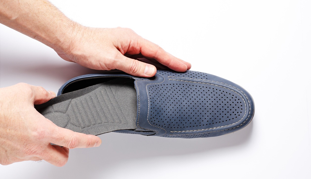 man putting an insole inside a shoe