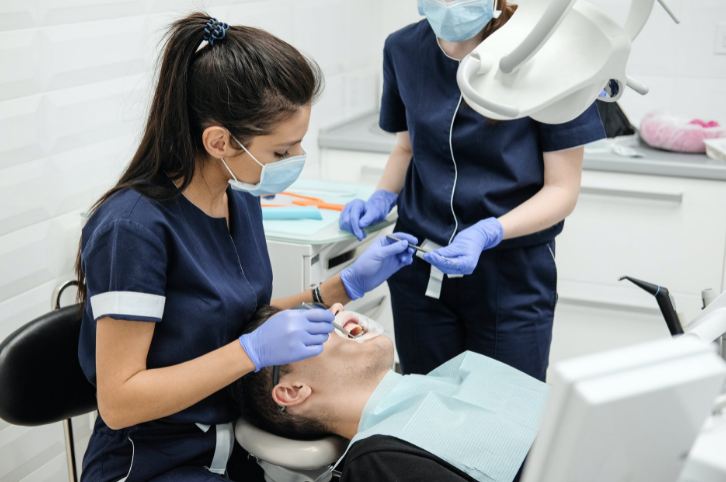 female-dentist-with-assistant-curing-teeth-of-patient