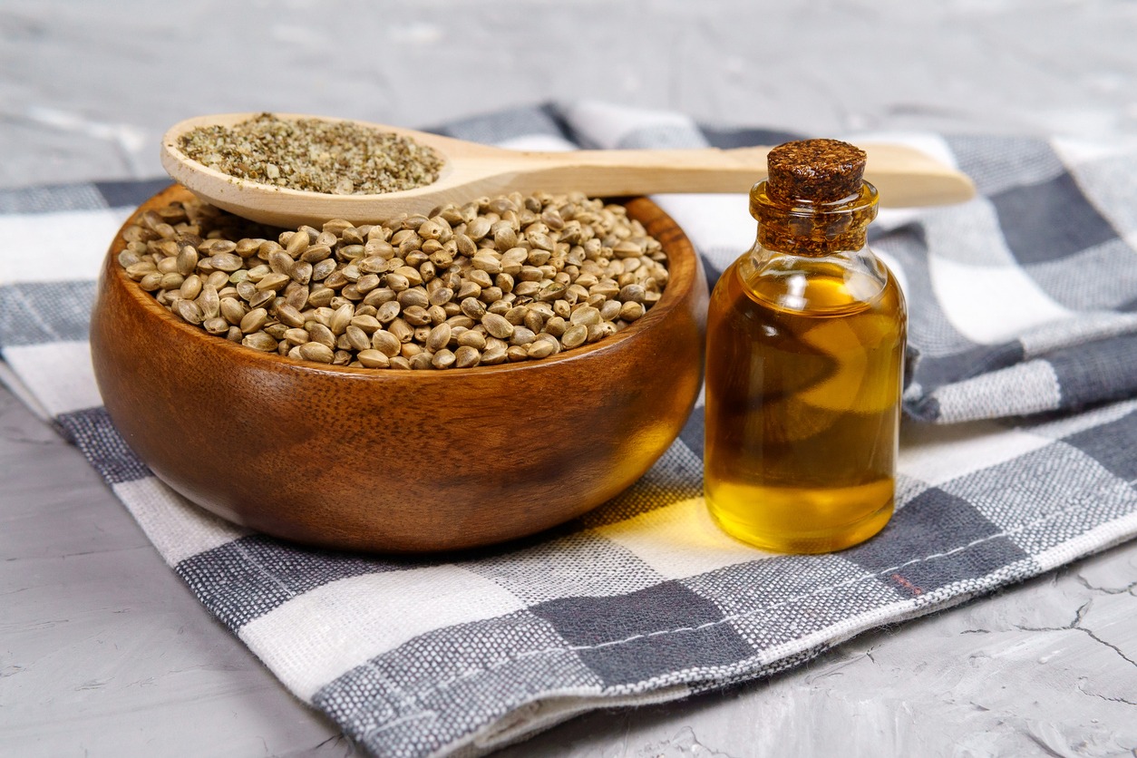 a bottle of hemp seed oil with a bowl of dried hemp seeds 