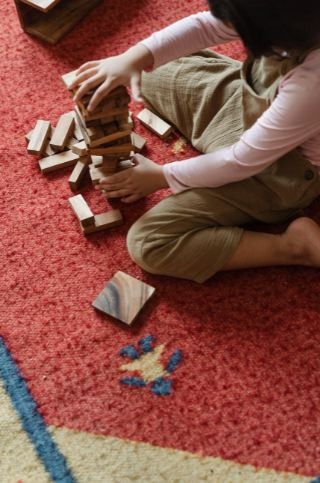 kid-playing-with-tower-game-blocks-on-floor