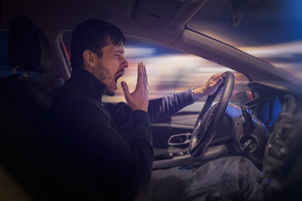 A man yawning behind the wheel at night