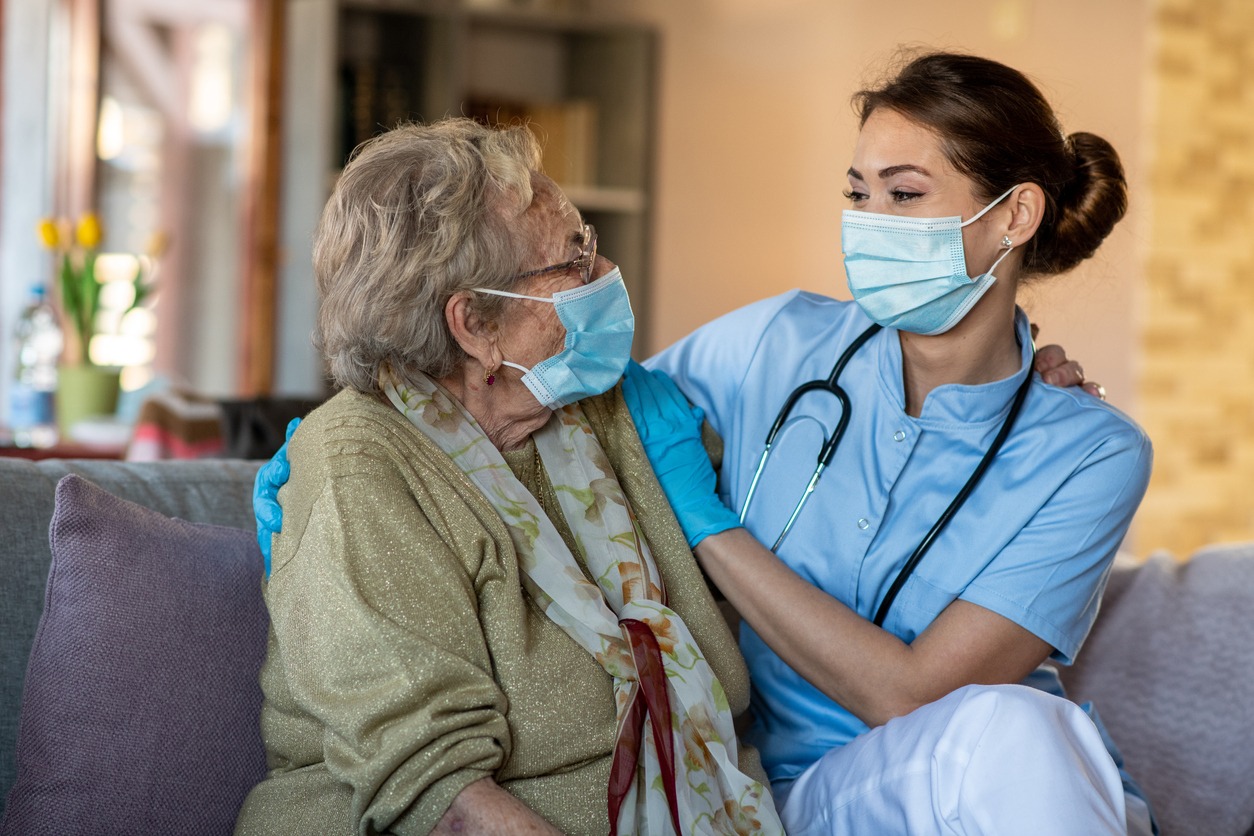an elderly woman talking to a young care specialist in a nursing home