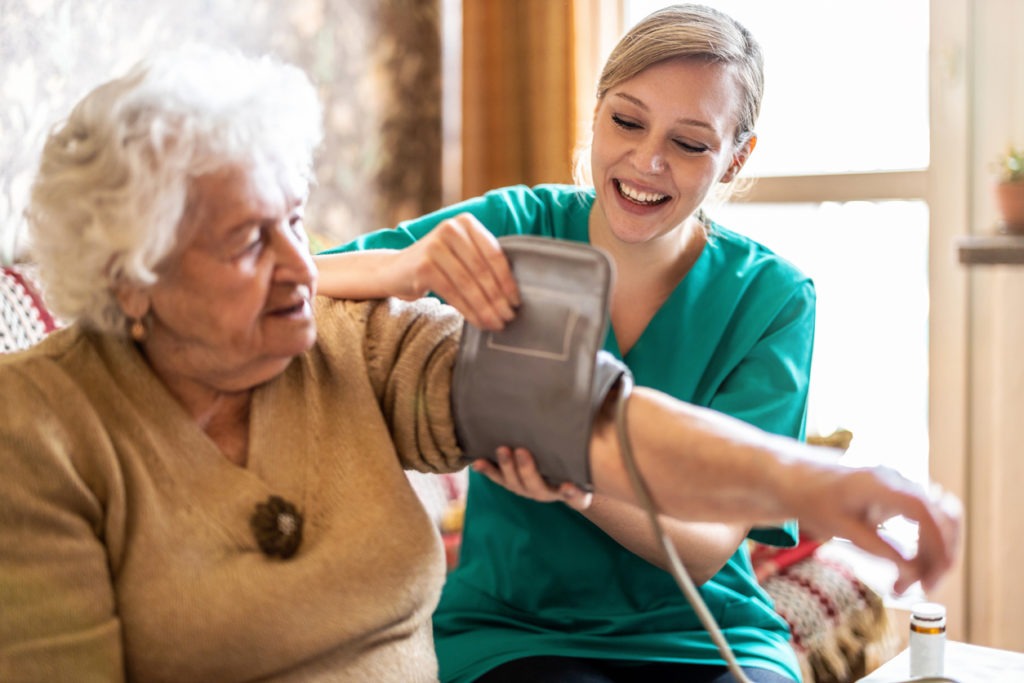 nurse checking the blood pressure of an elderly woman