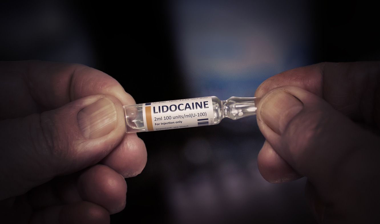 person holding a tube of lidocaine