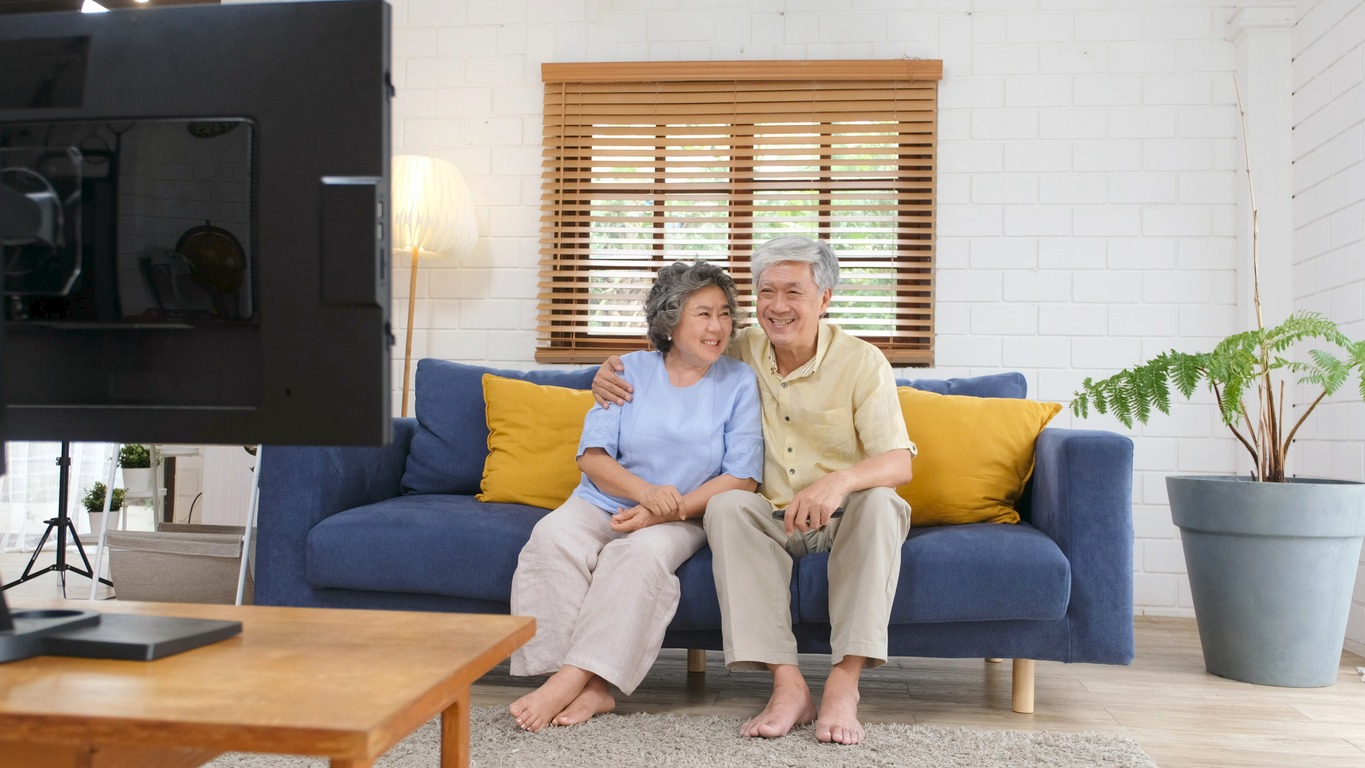 two older adults at home enjoying watching TV