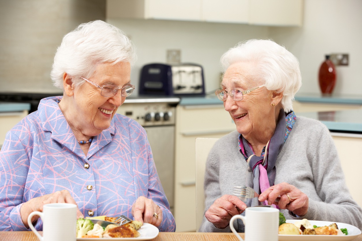 two older adults eating together